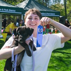 Teen boy holding puppy and a blue prize ribbon